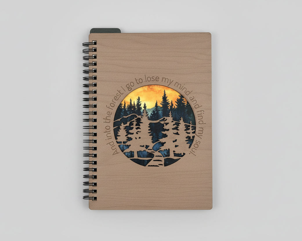 Notebook with a forest design and text on a wooden surface