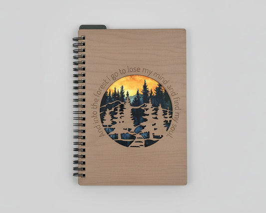Notebook with a forest design and text on a wooden surface